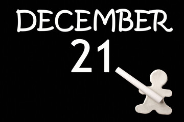 A small white plasticine man writing the date 21 December on a black board. Business concept. Education concept.
