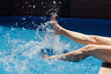 Young european woman legs kicks in the pool splashes water. Concept, carefree, summer, vacation.