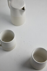 Big set of empty white ceramic plates and other tableware different size and shapes over white linen tablecloth. Flat lay