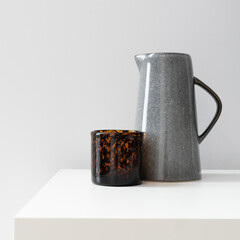 A ceramic kettle and an amber glass are on the table