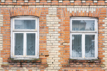 Brick wall wooden window. Old architecture. Abandoned factory wall. Grunge brick wall texture. Wooden window frame. White peeling paint destroyed building.