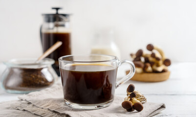 Healthy trendy coffee with mushrooms in cup, coffee pot, milk on white wooden background