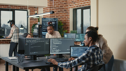 Programmer analyzing compiling code on multiple screens takes off glasses and doing high five hand...