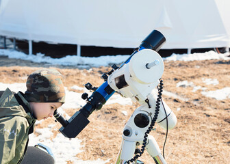 Child boy watching the sun through a telescope on a tripod at the observatory for observation of...
