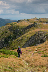 Obraz premium A woman hikes on top of the mountains in an amazing landscape. Hiking and trekking are very healthy sports.