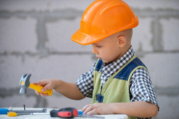 Kid in hard hat holding hammer. Little child helping with toy tools on construciton site. Kids with construction tools. Kids builder and repair construction worker.