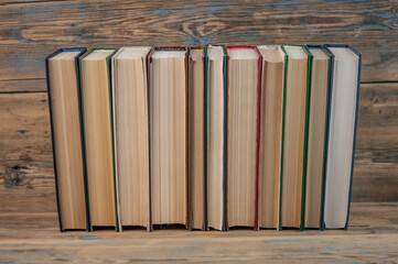 Stack of books on wooden table over rustic background with copy space