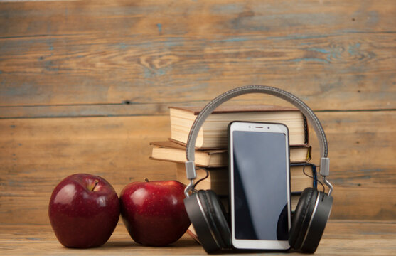 stack of books with red apple and digital tablet, headphone  on the wood table with blackboard