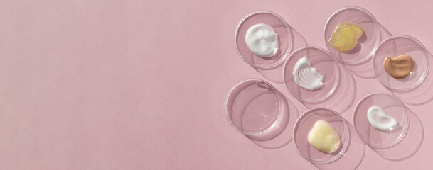 Multicolored texture of cream, scrub, serum, oil and hyaluronic acid in Petri dishes on a pink background. Concept of cosmetics laboratory researches. Smear of skincare cosmetics product. Banner