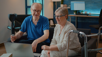 Couple with chronic disability giving high five after success on laptop, celebrating teamwork and...