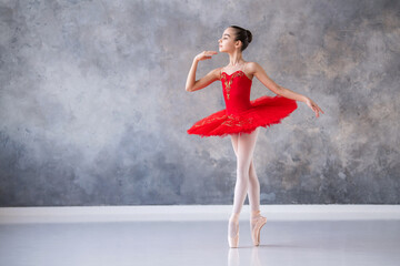 A cute little girl dreams of becoming a professional ballerina. A girl in a bright red tutu on...