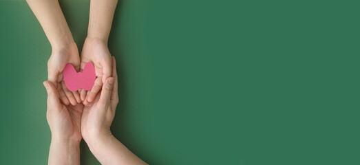 World Thyroid Day. Adult and child holding paper form of the thyroid gland on green background....