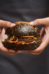 Black burger and french fries on wooden background