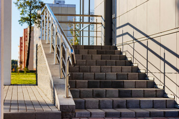 A ramp and metal railings at the entrance to the residential building for the convenience of people with disabilities and the elderly.