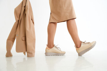 Beautiful sneakers on woman legs in the studio on white background. Fashionable shooting of a young girl with beautiful legs