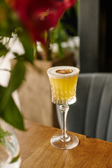 yellow alcoholic cocktail or lemonade with foam and a piece of dry lemon on the background of a beautiful restaurant, vertical image