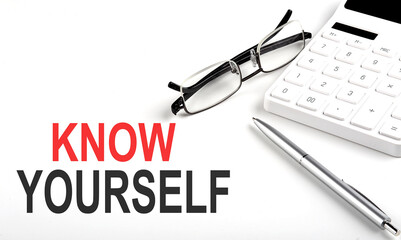 KNOW YOURSELF Concept. Calculator,pen and glasses on white background