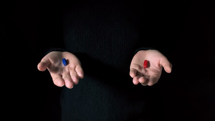 Red and blue pills on hands isolated on a black background