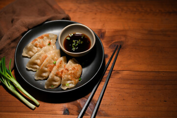 Homemade gyoza or Asian fried dumplings served with sauce and spring onion