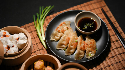 Gyoza in a black plate with special sauce, Steamed Chinese pork buns