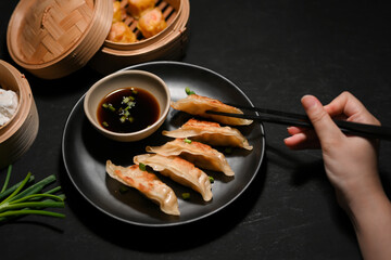 Female enjoy eating Asian fried gyoza or fried dumplings with chopsticks