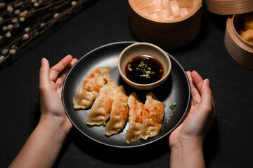 Close-up image a Female hands holding a plate of tasty fried dumplings