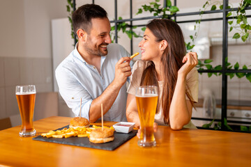 Couple drinking beer and eating burgers