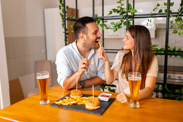 Couple having fun eating burgers and drinking beer