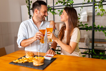 Couple making a toast while eating burgers and drinking beer