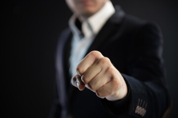 Business man hand clenched fist on dark background
