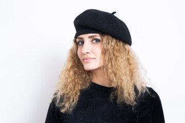 Fototapeta premium Hünsche junge Frau mit roten Locken, einem schwarzen Kleid und einem schwarzen Béret. Eine junge Künstlein.