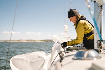 Woman folding sails on boat