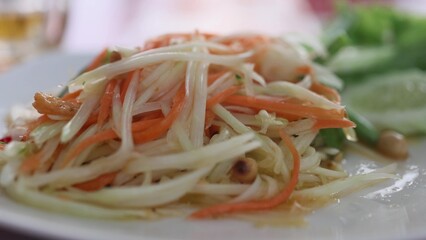 Close up of fresh yummy delicious Thai traditional popular street food spicy green papaya salad or Som Tam in dish