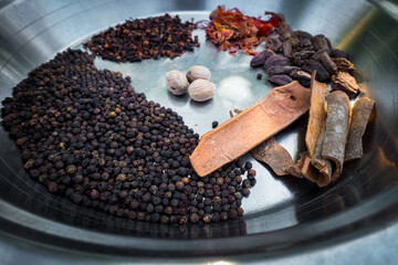 A close up shot of dried whole Indian spices on a big metal bowl.