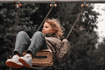The girl swung strongly on the swing. Happy child spends time on the playground.