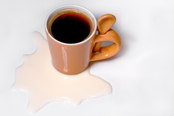 A cup of black coffee with milk on a white table, isolated. Spilled milk.