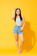 Pretty Asian female model wearing summer outfit posing in studio yellow isolated background