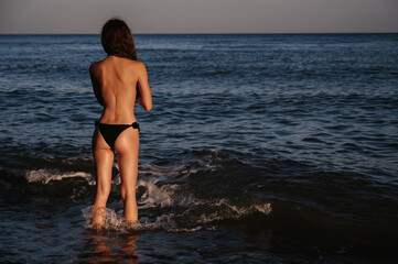 young topless girl with a sexy ass is sunbathing on the beach by the sea in summer on vacation