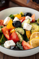Bowl of fresh greek salad on wooden background
