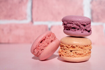 Colored macaroons close-up on a pink background. Side view, space for text.