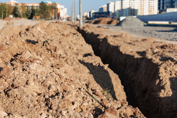 A trench in the ground prepared for laying the electrical cable at the construction site.
