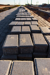 Pavement repairs and paving slabs laying on the prepared surface, with tile cubes in the background. Laying paving slabs in the pedestrian zone of the city. Paving slabs and curbs.