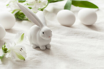 Fototapeta na wymiar White easter background with white rabbit, white eggs and flowers