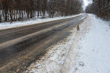 Obraz premium Winter road outside the city, cleared of snow in the countryside. Large snowdrifts on the side of the road