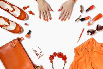 Women's hands with manicure and items of women's clothing and accessories in orange on a white background.