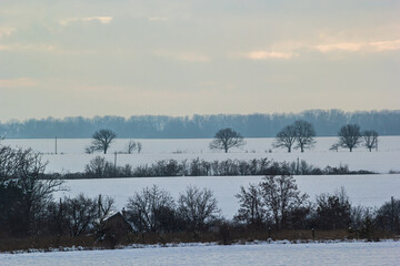 Natural sunset sunrise over field or meadow. The color of the sky over the winter snowy ground. Landscape under a picturesque sky at sunset. Dawn of the sun.
