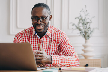 Young smiling african american businessman talking with business partner by video call on laptop