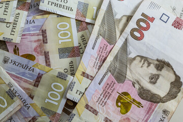 Ukrainian paper money is laid out on a blue background. 100 hryvnia banknotes
