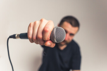 good-looking European young bearded man with mustache tattoos and microphone looking into the...