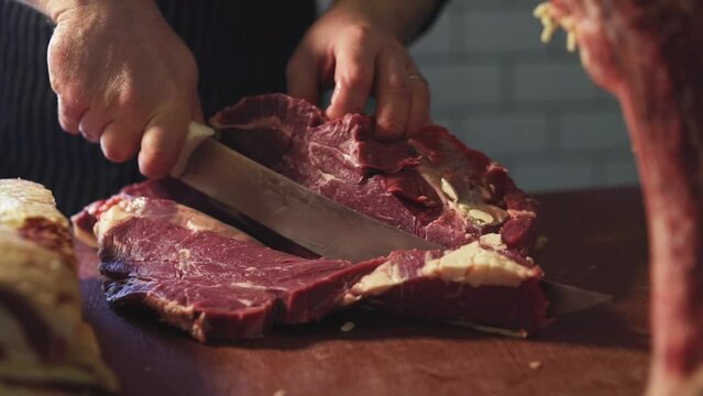 Butcher cuts a steak with a butcher's knife from a block of meat.